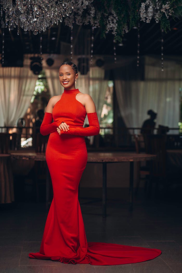 Services Smiling woman in a stunning red gown posing indoors for a fashion shoot.