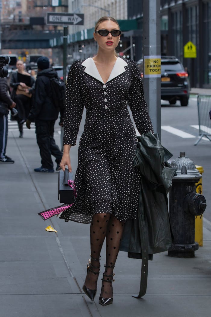Services Stylish woman in polka dot dress walking in NYC street with sunglasses.